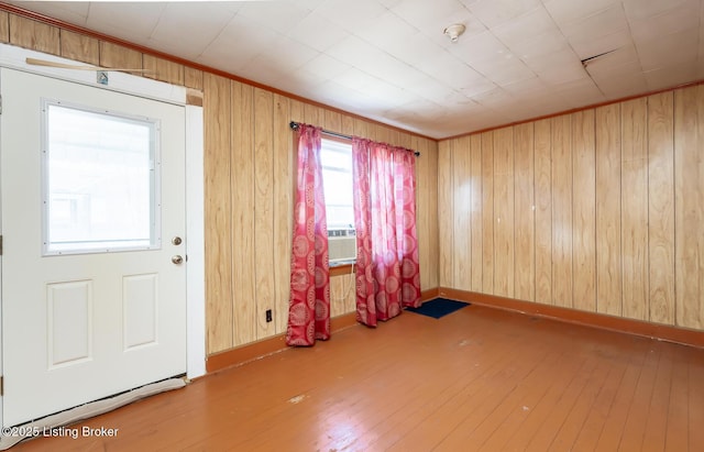 foyer with crown molding, wood walls, hardwood / wood-style flooring, and baseboards