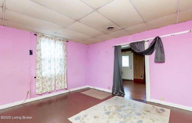 spare room featuring visible vents, a paneled ceiling, and baseboards