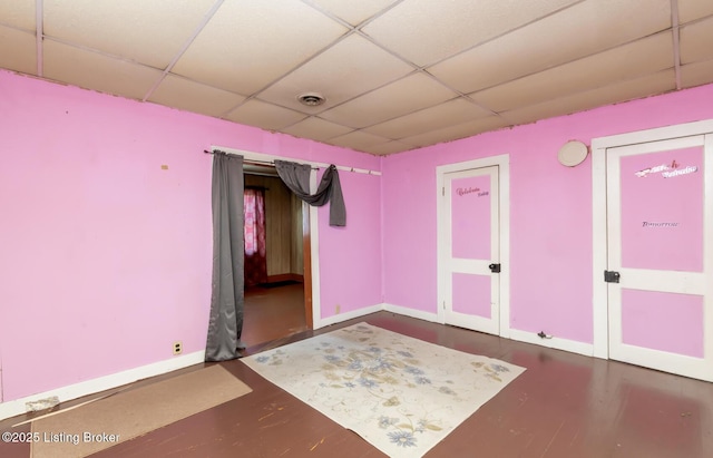 spare room with a paneled ceiling, visible vents, and baseboards