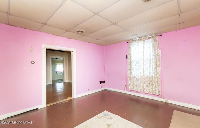 unfurnished room featuring visible vents, a paneled ceiling, and baseboards