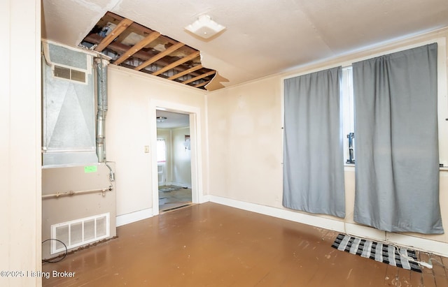 spare room featuring finished concrete flooring, baseboards, and visible vents