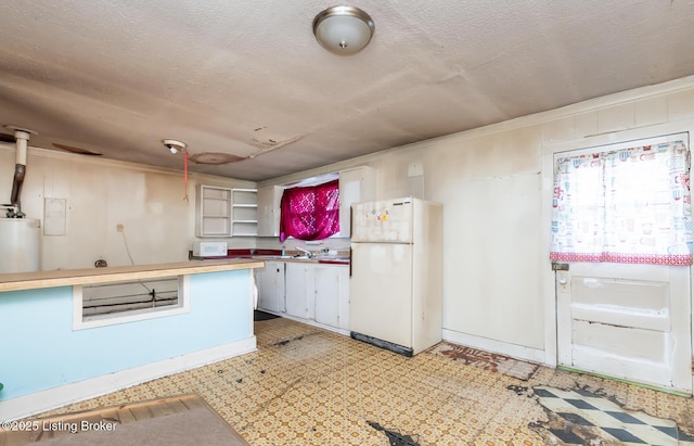 kitchen with a textured ceiling, open shelves, water heater, freestanding refrigerator, and light floors