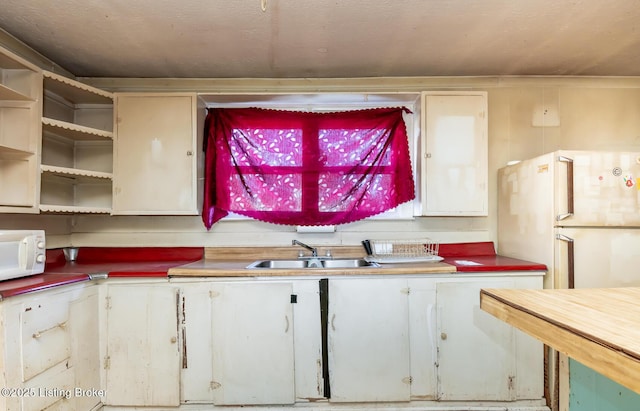 kitchen featuring white appliances, white cabinets, and a sink