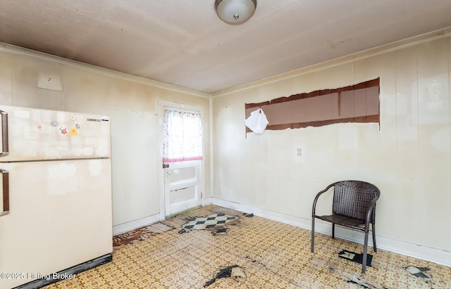 interior space with baseboards, crown molding, freestanding refrigerator, and tile patterned floors