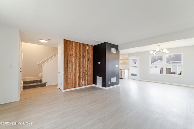 unfurnished living room with stairway, light wood-type flooring, visible vents, and baseboards