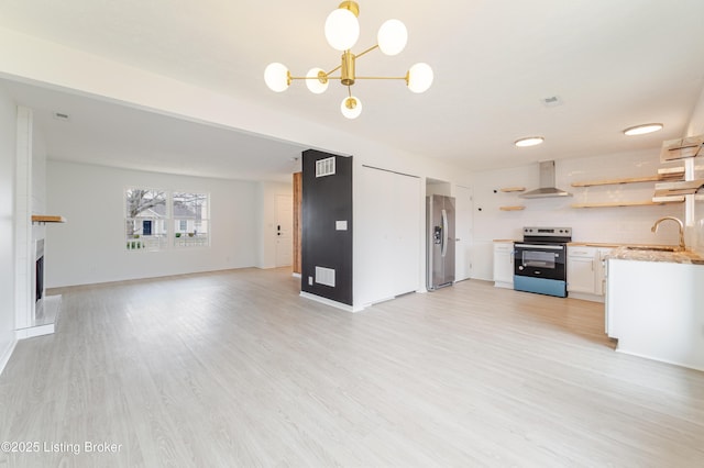 kitchen featuring electric stove, open shelves, open floor plan, wall chimney range hood, and stainless steel fridge