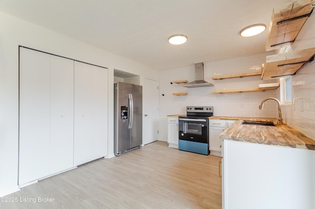 kitchen featuring stainless steel appliances, a sink, wall chimney range hood, and open shelves