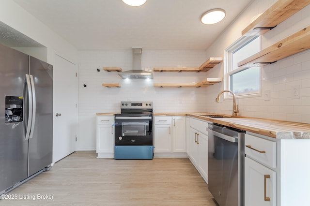 kitchen with stainless steel appliances, a sink, wooden counters, wall chimney range hood, and open shelves