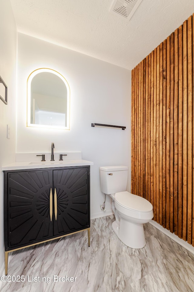 bathroom with visible vents, toilet, marble finish floor, a textured ceiling, and vanity