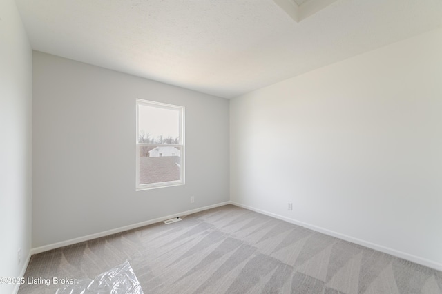 spare room with carpet flooring, visible vents, and baseboards