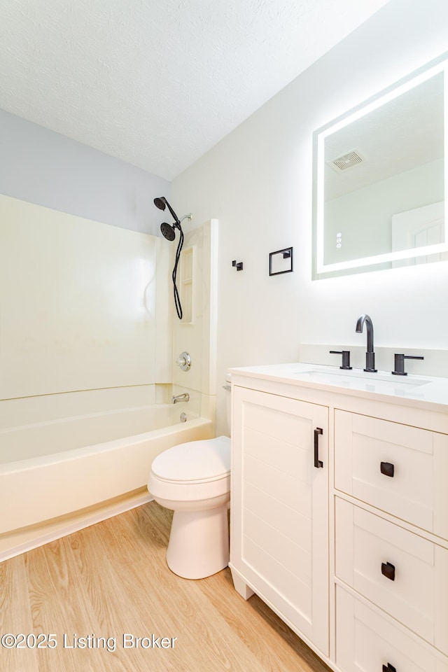 full bathroom with visible vents, toilet, wood finished floors, a textured ceiling, and shower / bathing tub combination