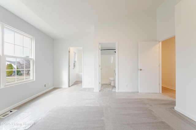 unfurnished bedroom featuring light carpet, visible vents, ensuite bath, and baseboards