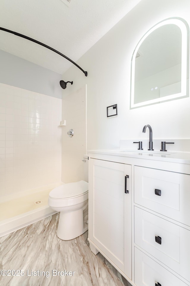 full bath featuring toilet, a textured ceiling, tiled shower, and vanity