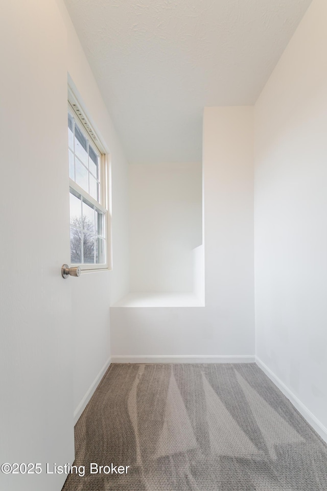 carpeted spare room featuring baseboards