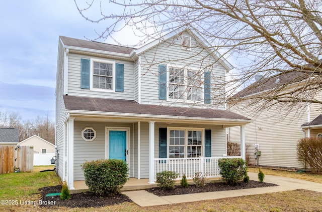 traditional-style house featuring covered porch and fence