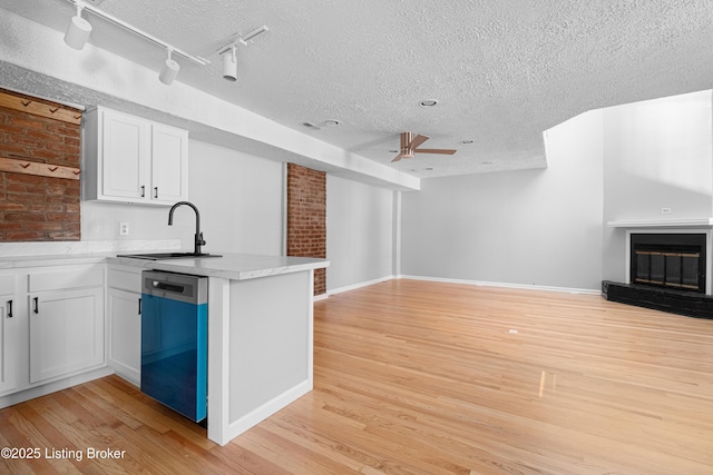 kitchen with a sink, white cabinetry, open floor plan, and dishwasher