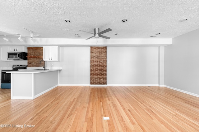 unfurnished living room with ceiling fan, light wood-type flooring, a sink, and baseboards