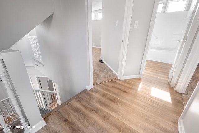 corridor featuring an upstairs landing, visible vents, light wood-style flooring, and baseboards