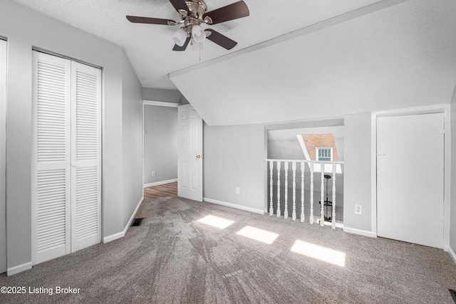 additional living space with carpet, lofted ceiling, visible vents, a textured ceiling, and baseboards