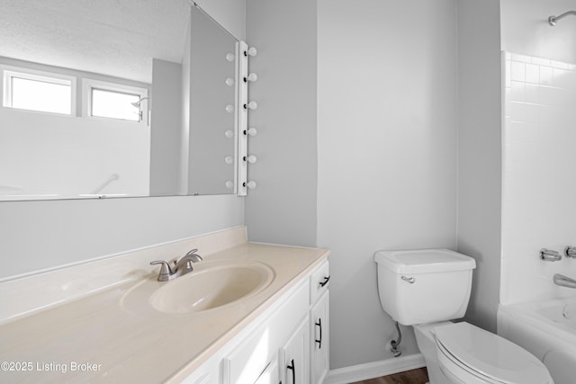 full bathroom featuring baseboards, toilet, a textured ceiling, vanity, and shower / bathing tub combination