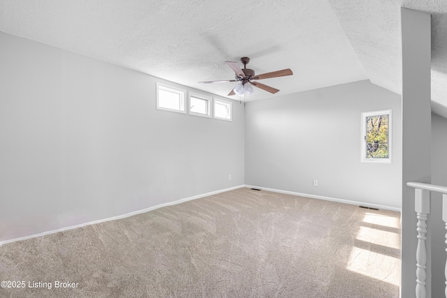 unfurnished room featuring baseboards, visible vents, ceiling fan, carpet, and a textured ceiling