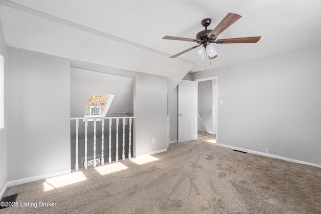 carpeted spare room with a textured ceiling, ceiling fan, visible vents, and baseboards