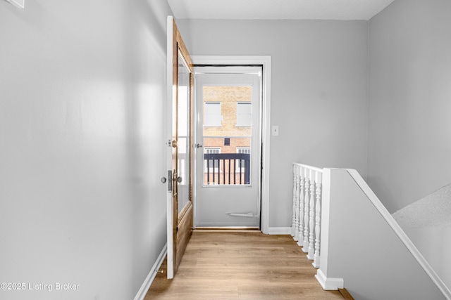 doorway to outside with light wood finished floors and baseboards