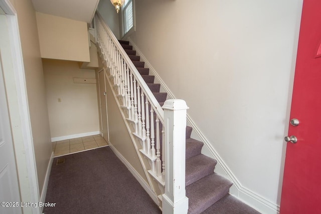 stairs with carpet floors, tile patterned flooring, and baseboards