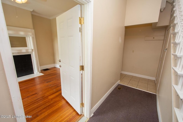 hall with visible vents, crown molding, baseboards, and wood finished floors