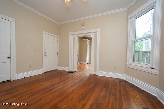 empty room featuring ornamental molding, dark wood-style flooring, and baseboards