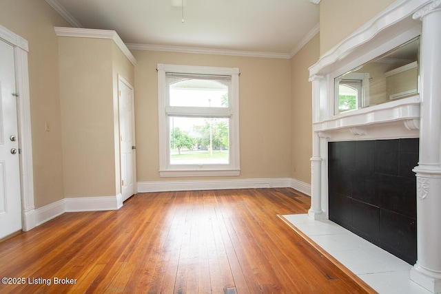 unfurnished living room featuring decorative columns, baseboards, wood-type flooring, and crown molding