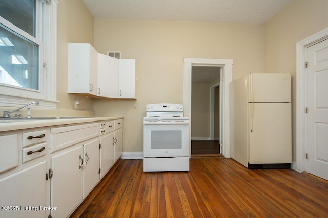 kitchen with light countertops, visible vents, white cabinets, a sink, and white appliances