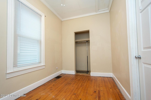 unfurnished bedroom with visible vents, light wood-style floors, baseboards, ornamental molding, and a closet