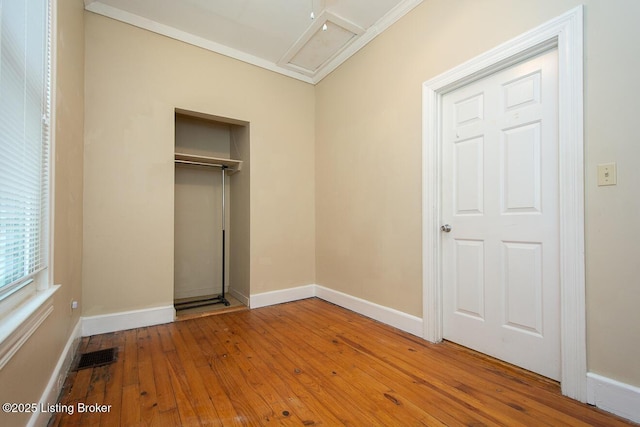 unfurnished bedroom featuring hardwood / wood-style flooring, baseboards, visible vents, and attic access