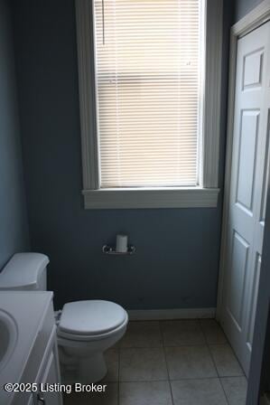 half bath featuring baseboards, vanity, toilet, and tile patterned floors