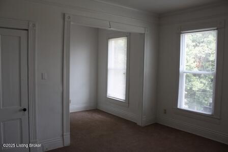 unfurnished room with plenty of natural light and dark colored carpet