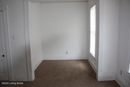 empty room featuring baseboards and dark carpet