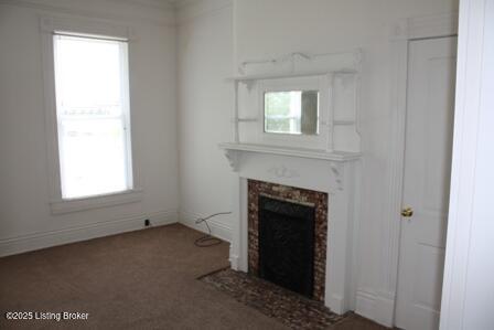 unfurnished living room with carpet and a fireplace with flush hearth