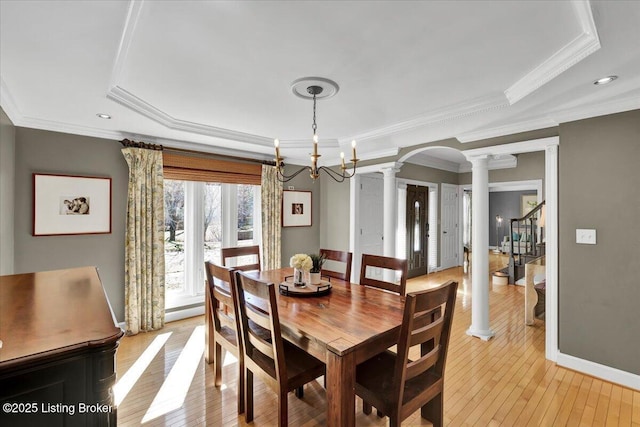 dining room with decorative columns, arched walkways, baseboards, stairs, and light wood-style floors