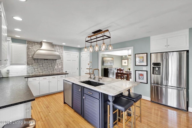 kitchen with decorative backsplash, appliances with stainless steel finishes, light wood-style floors, white cabinets, and a sink