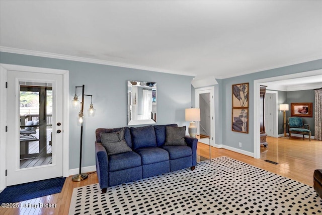 living area with crown molding, baseboards, and wood finished floors