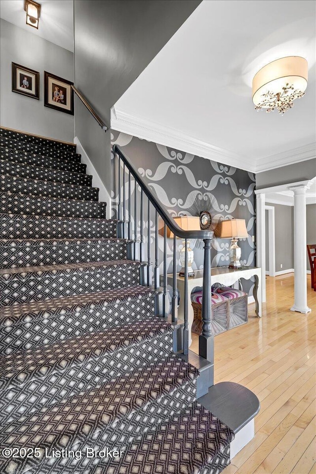 stairway with ornate columns, baseboards, ornamental molding, and hardwood / wood-style floors