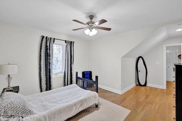 bedroom with vaulted ceiling, a ceiling fan, light wood-style flooring, and baseboards