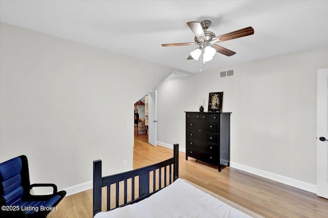 bedroom with a ceiling fan, wood finished floors, visible vents, and baseboards