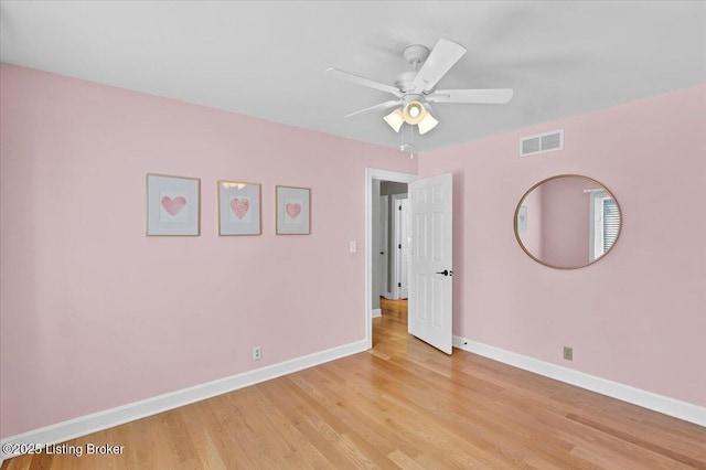 empty room featuring light wood-type flooring, visible vents, and baseboards