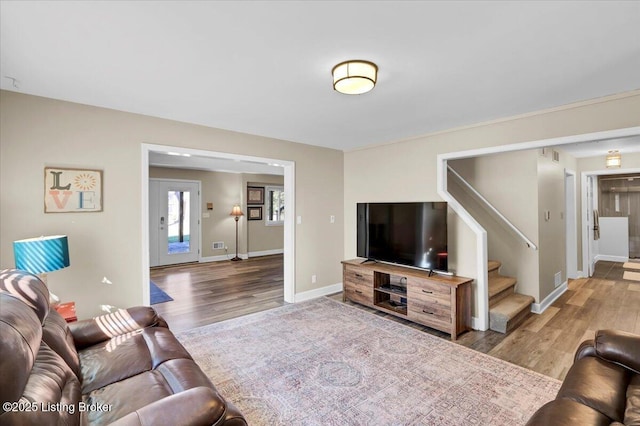 living area with wood finished floors, baseboards, and stairs