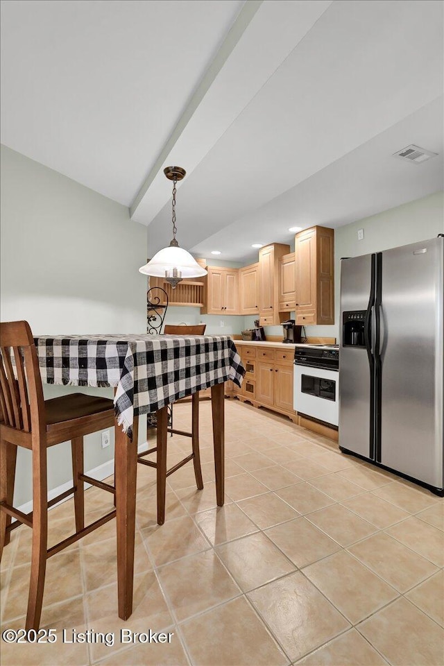 kitchen with light tile patterned floors, visible vents, stove, light brown cabinets, and stainless steel fridge with ice dispenser