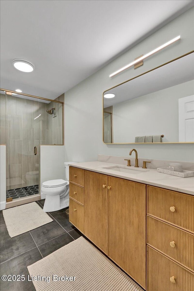 bathroom featuring tile patterned flooring, a shower stall, toilet, and vanity