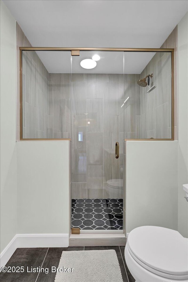 full bath with a stall shower, baseboards, and toilet