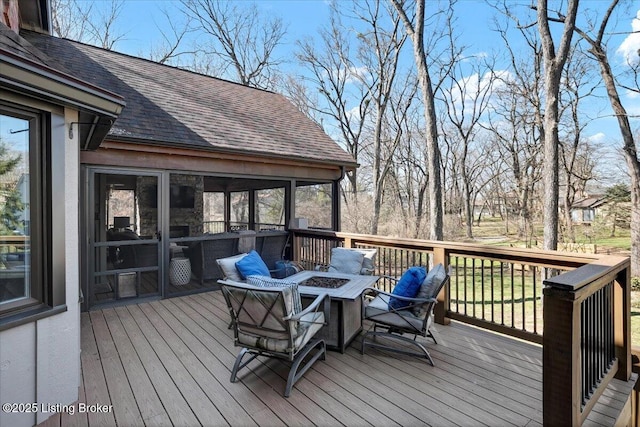 deck with a sunroom and a fire pit